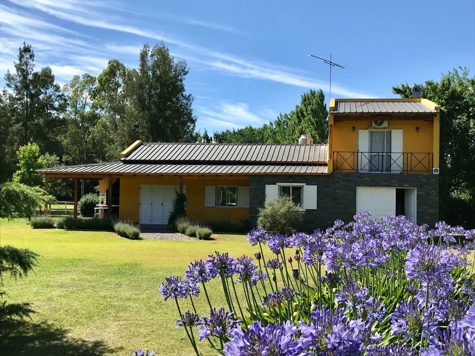 Fachada de La Calandria Casa de Campo con jardín y flores